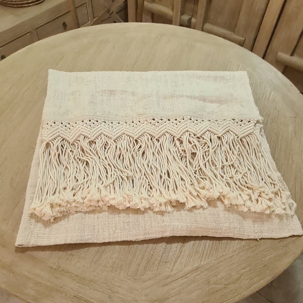 A natural cream-colored woven throw with a fringe tassel border