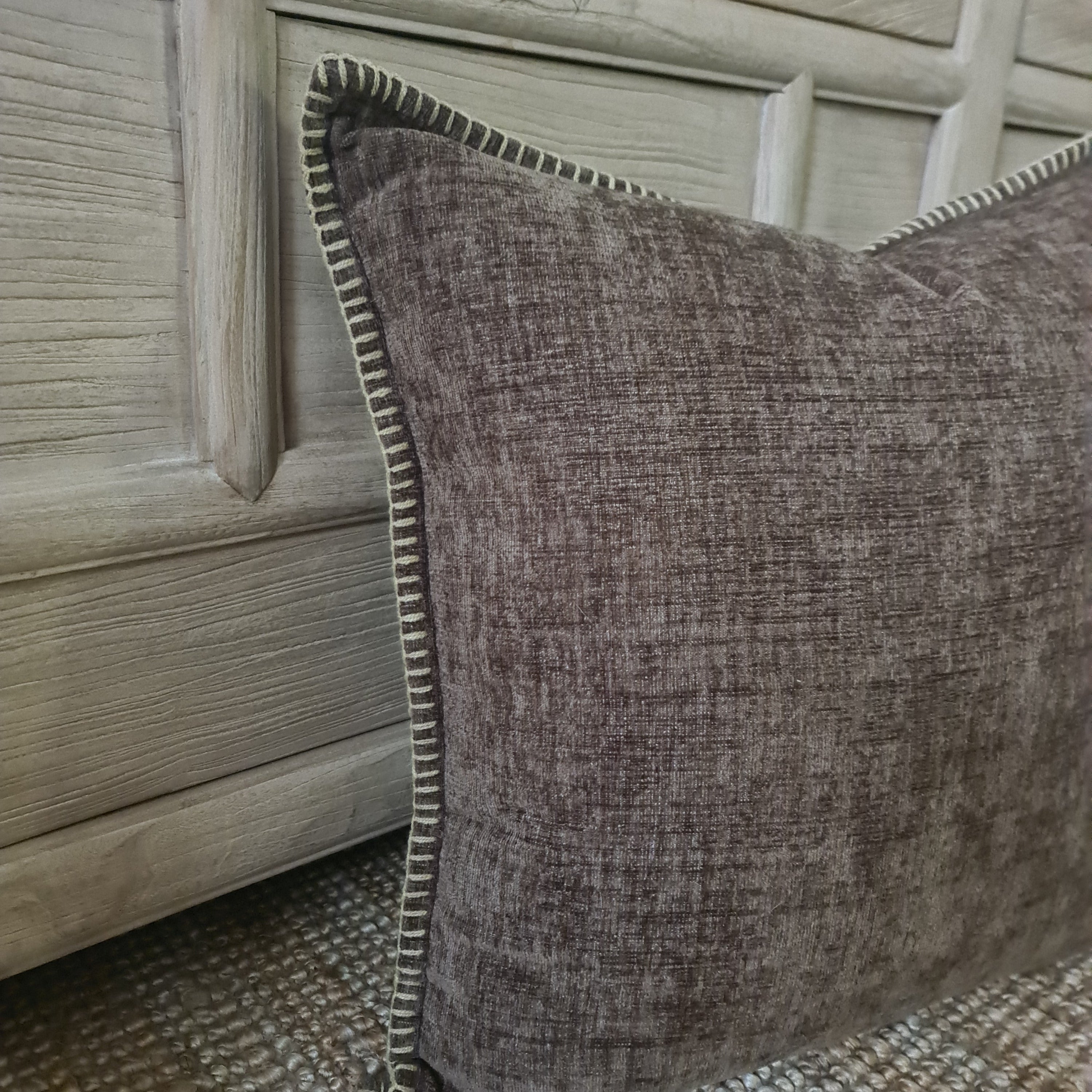 Textured brown pillow leaning against a wooden cabinet.