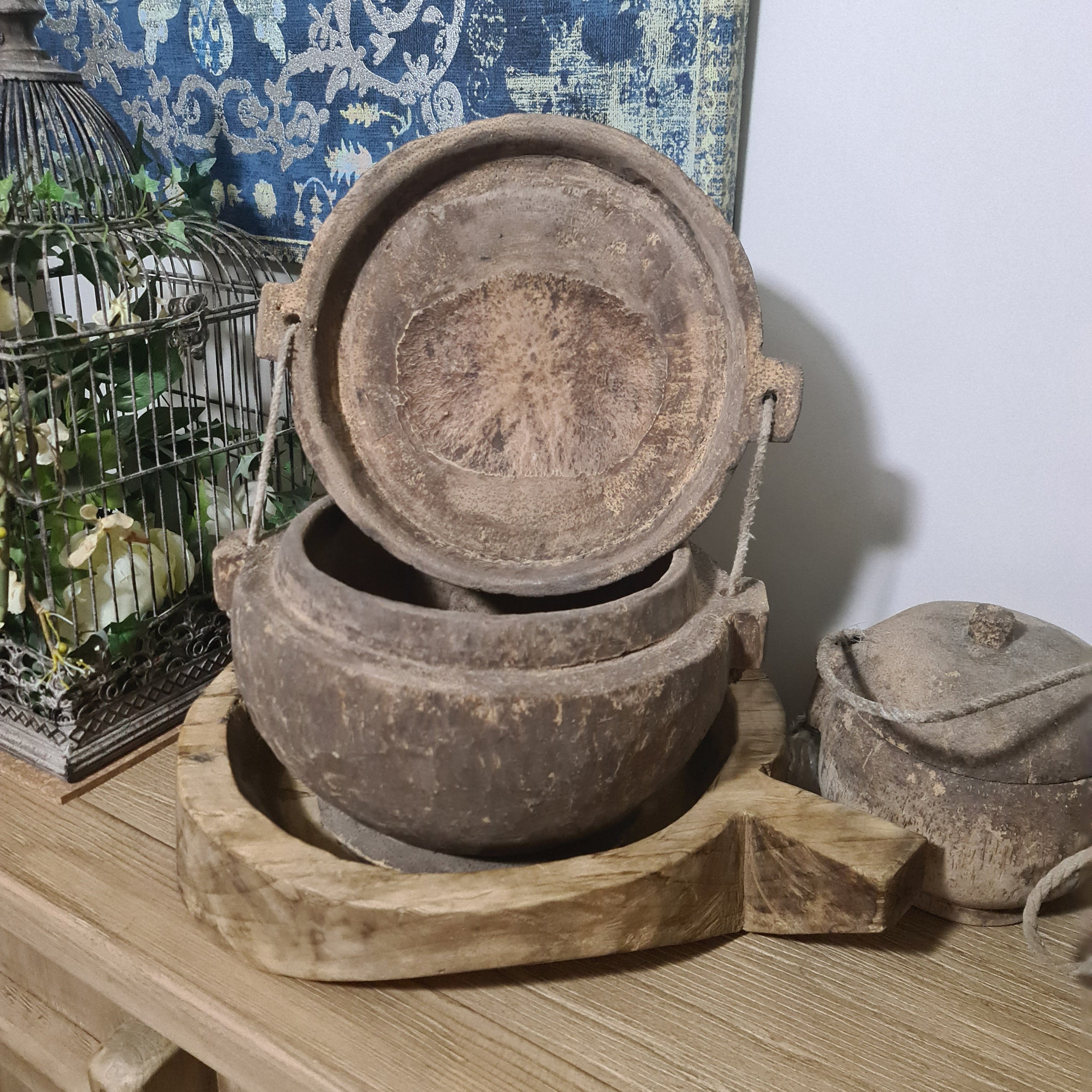 Old metal pot on a wooden stand with a decorative rug in the background